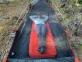 A person relaxes inside a tent on a bright orange Therm-a-Rest NeoAir XLite sleeping pad, enjoying the outdoors.