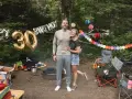 Couple celebrates 30th birthday with fun camping birthday ideas. Balloons and colorful banners decorate the campsite.