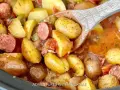 A wooden spoon scoops up hearty potatoes and sausage from a crockpot, perfect for camping crockpot meals.