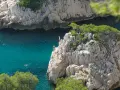 Adventurous swimmers enjoy the turquoise waters of the calanques of Cassis, with some daring to cliff jump from rocky outcrops.