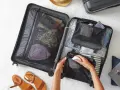 Hands packing a suitcase with clothes, passport, and accessories. Discover smart camping packing hacks for an organized trip.