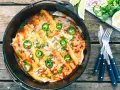 Delicious dutch oven enchiladas, topped with melted cheese, jalapeños, and cilantro, ready to be served.