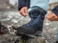 Hands tying laces on a new pair of Han Wag hiking boots, ready for breaking them in on the trail.