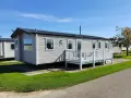 A row of modern mobile homes, perfect for a **location vacances mobil home**, sit under a clear blue sky.