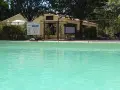 A refreshing pool awaits at this camping in Aix en Provence. A sign details pool depths, and a man stands near the reception building.