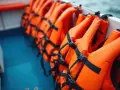 A row of bright orange type iii life jackets are neatly stored on a boat, ready for an adventure on the water.