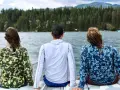 Three friends enjoy a lake view, wearing cooling clothing for extreme heat. The camouflage and blue patterned shirts offer sun protection.