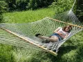A woman relaxes in a spacious double hammock, enjoying a sunny day outdoors.