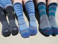 Four pairs of colorful hiking socks, some with stripes, others with logos, ready for adventure.