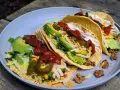 A plate of delicious camp taco with avocado, salsa, cheese, and sour cream, perfect for an outdoor meal.