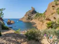 A vibrant scene of camping calanques, with people enjoying the turquoise waters and rocky shores under a clear blue sky.