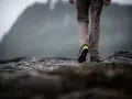 Choosing hiking boots is key for a good trek. This person walks on rocky terrain, showing off their sturdy footwear.