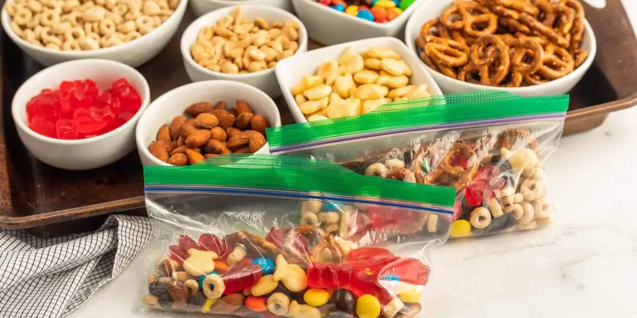 Bags of colorful trail mix bar ingredients: cereal, nuts, pretzels, candy, and dried fruit, ready for snacking.