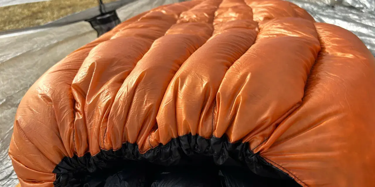 A bright orange sleeping bag with puffy baffles, ready for a cold night. This z pack 20 degree bag is perfect for camping adventures.