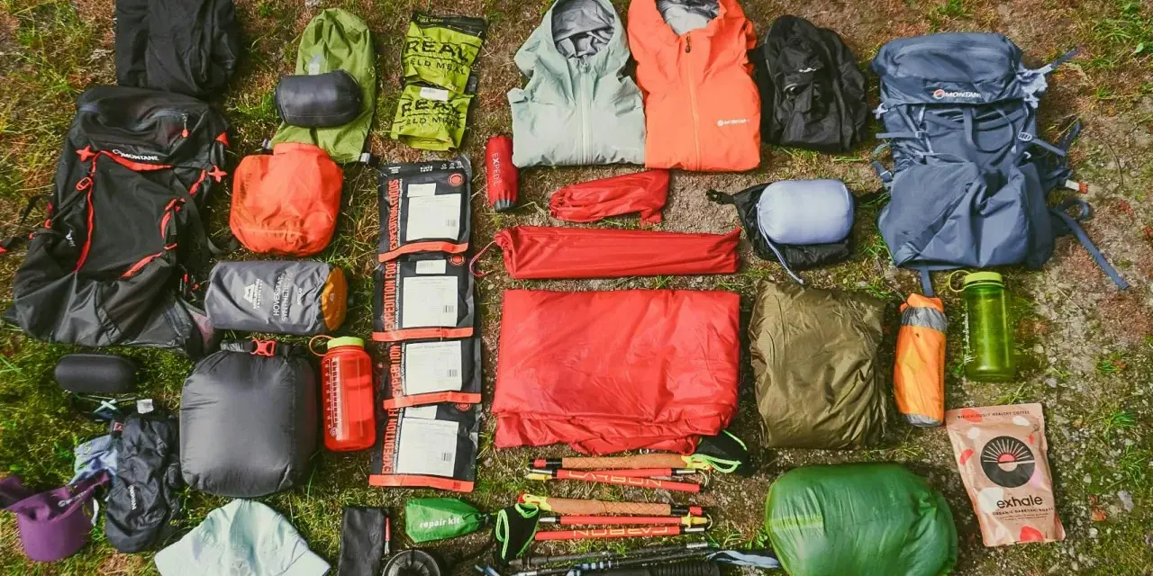 A comprehensive fastpacking gear list, including backpacks, sleeping bags, tents, jackets, food, and trekking poles, laid out on grass.