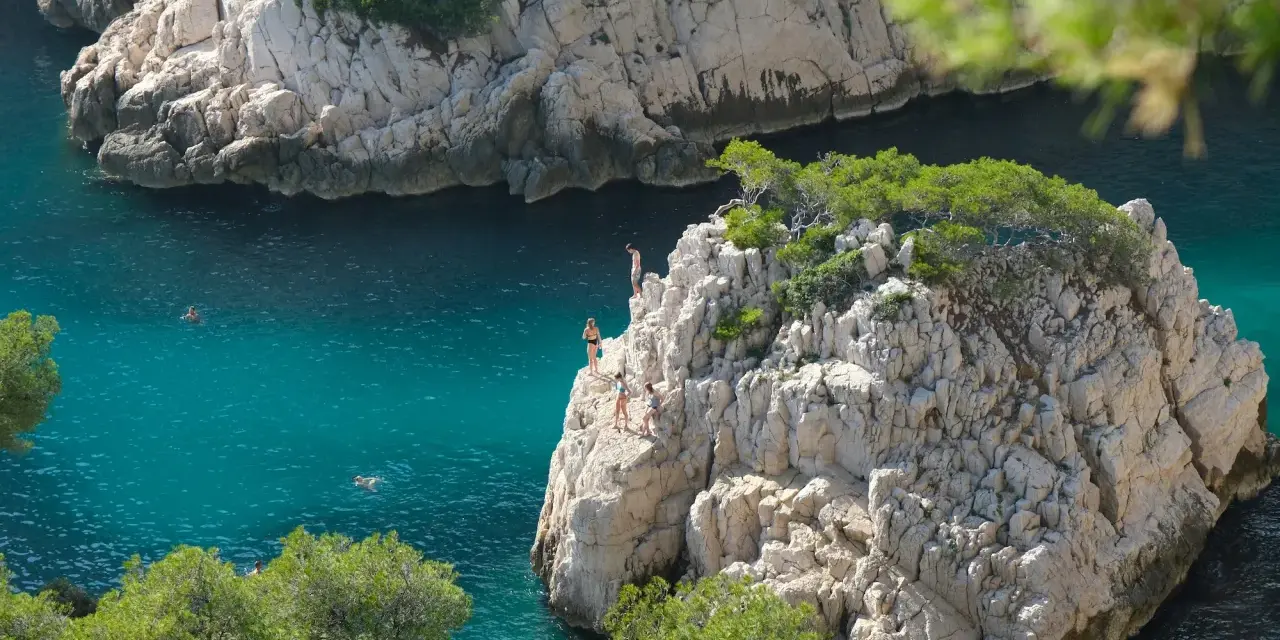 Adventurous swimmers enjoy the turquoise waters of the calanques of Cassis, with some daring to cliff jump from rocky outcrops.