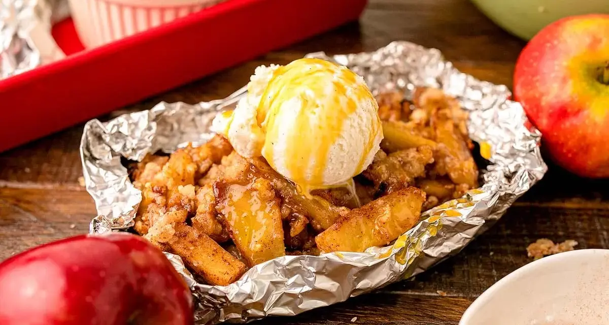 Warm campfire apples, baked in foil, topped with a scoop of vanilla ice cream and drizzled with caramel.