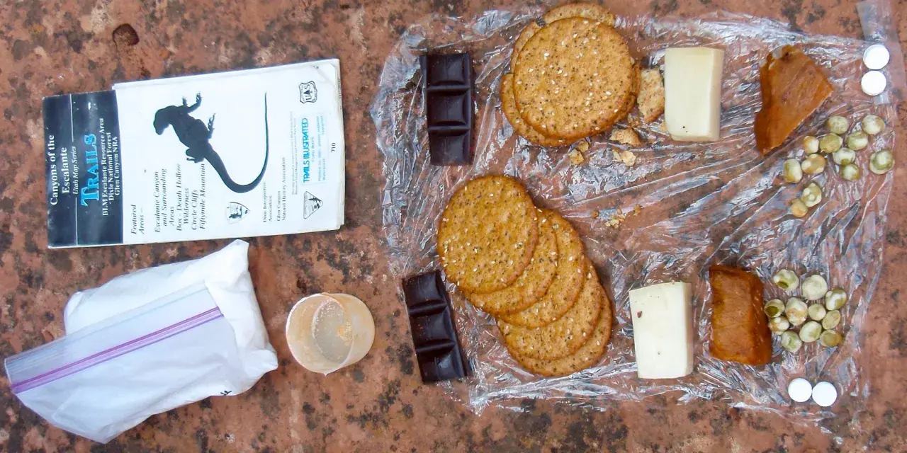 Backpacking lunch ideas no cooking: crackers, cheese, chocolate, dried peas, and jerky laid out on a map.