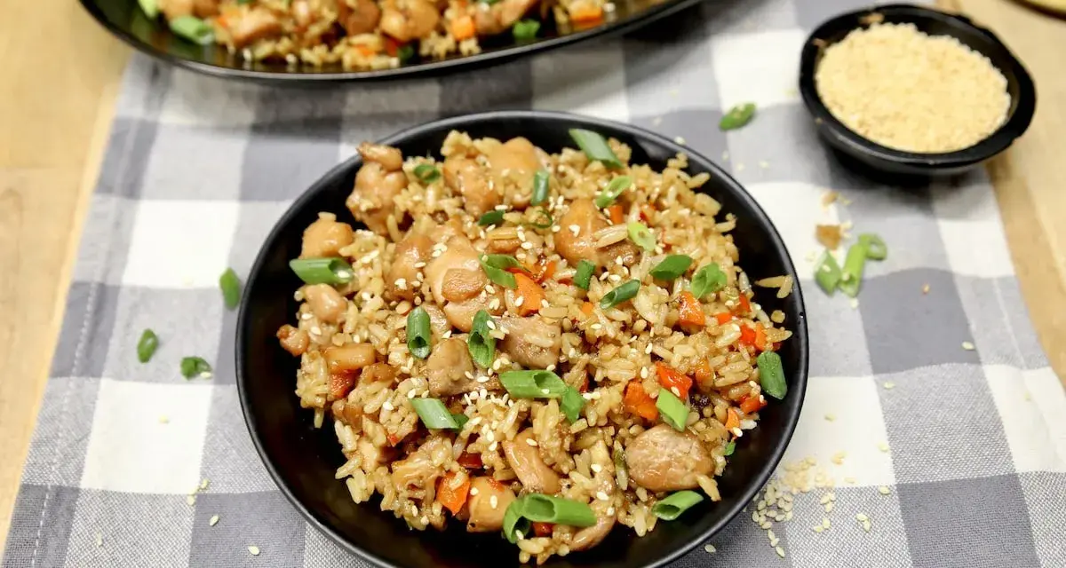 Chicken fried rice, a delicious dish perfect for learning how to cook rice on a Blackstone. Garnished with green onions and sesame seeds.