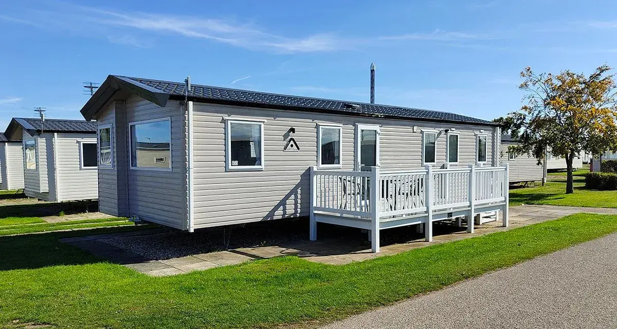 A row of modern mobile homes, perfect for a **location vacances mobil home**, sit under a clear blue sky.