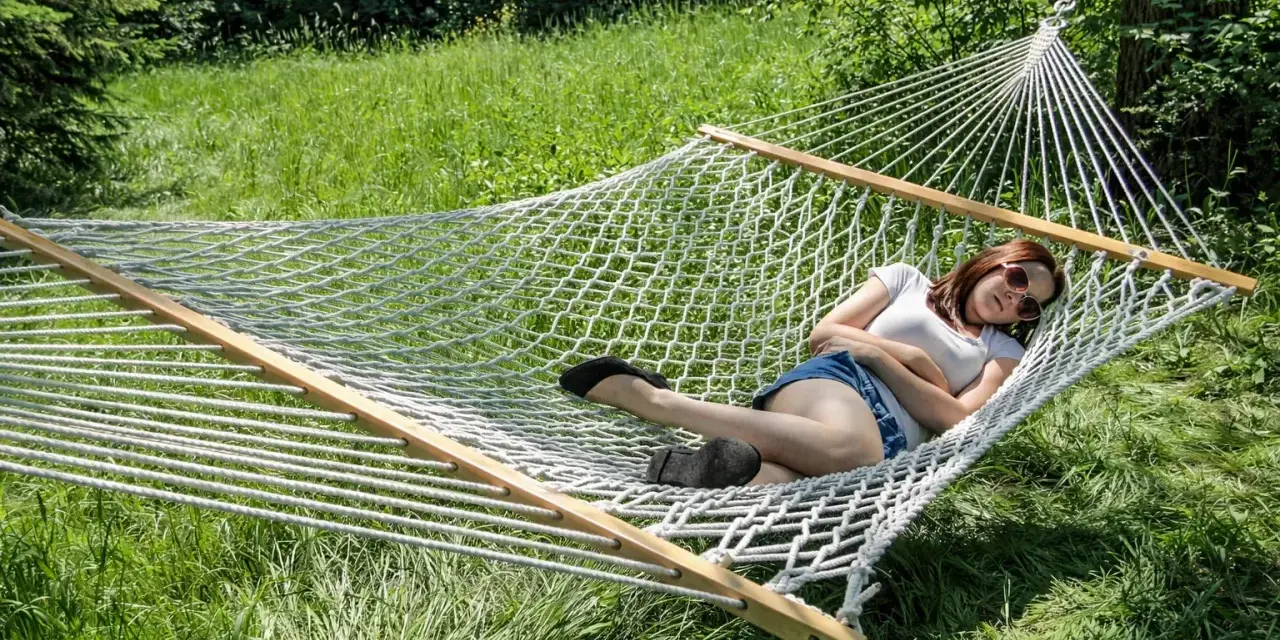 A woman relaxes in a spacious double hammock, enjoying a sunny day outdoors.