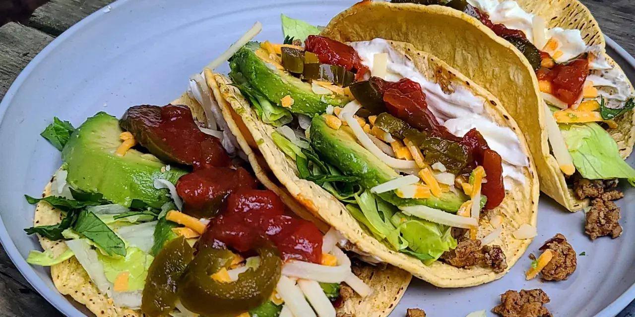 A plate of delicious camp taco with avocado, salsa, cheese, and sour cream, perfect for an outdoor meal.