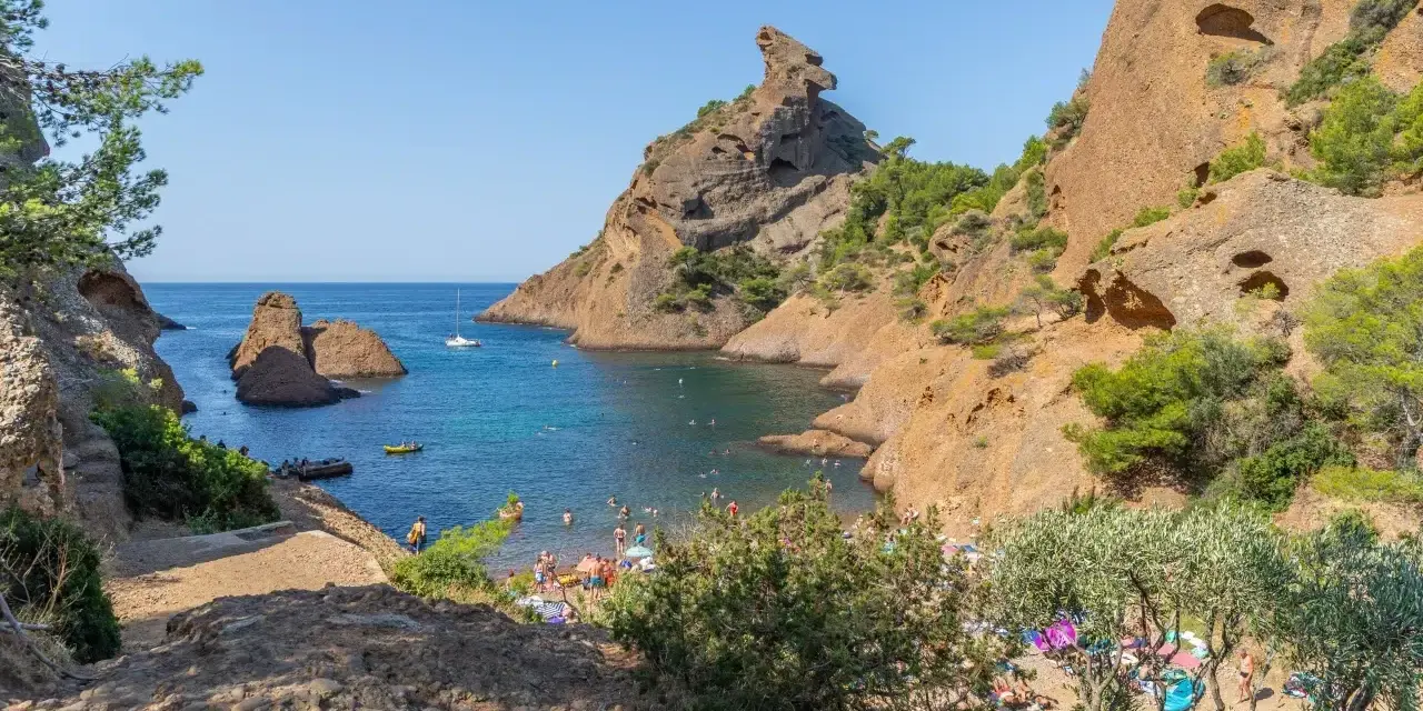 A vibrant scene of camping calanques, with people enjoying the turquoise waters and rocky shores under a clear blue sky.
