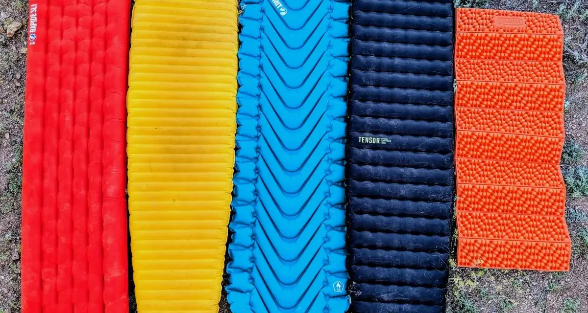 Five camping sleeping pads in red, yellow, blue, black, and orange. The black Nemo Tensor is the quietest sleeping pad for a peaceful night's sleep.