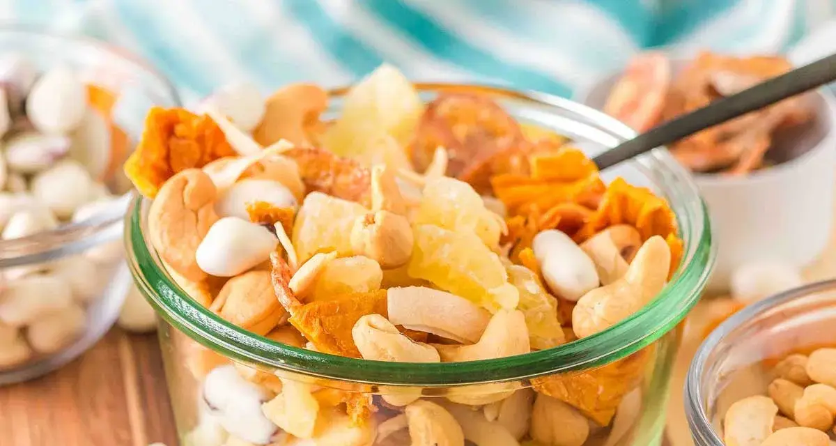 A delicious tropical trail mix recipe with cashews, dried pineapple, and coconut flakes in a glass bowl.