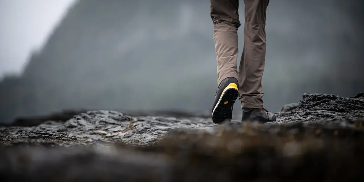 Choosing hiking boots is key for a good trek. This person walks on rocky terrain, showing off their sturdy footwear.