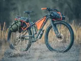 A fully loaded bike camping setup with panniers, frame bags, and handlebar roll, ready for an adventure.