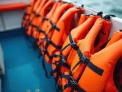 A row of bright orange type iii life jackets are neatly stored on a boat, ready for an adventure on the water.