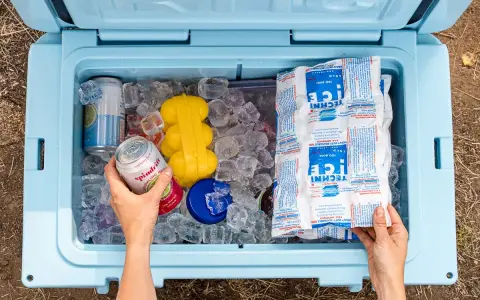 Hands packing a cooler with ice, cans, and reusable ice packs. This shows how to pack a cooler for a perfect picnic.