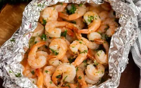Juicy shrimp and tender potatoes cooked in foil packets in the oven, seasoned with herbs.