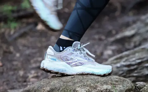 A Brooks Caldera trail running shoe on a rock, illustrating the heel drop for a runner.