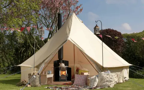 A cozy bell tent with a wood-burning stove inside, showcasing what is glamping: comfort and nature combined.