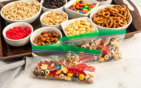 Bags of colorful trail mix bar ingredients: cereal, nuts, pretzels, candy, and dried fruit, ready for snacking.