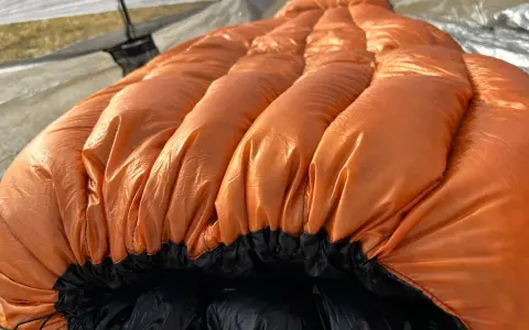 A bright orange sleeping bag with puffy baffles, ready for a cold night. This z pack 20 degree bag is perfect for camping adventures.