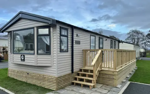 A beige Swift Provence mobil home with a wooden deck and steps. This idyllic location in Provence offers a cozy getaway.