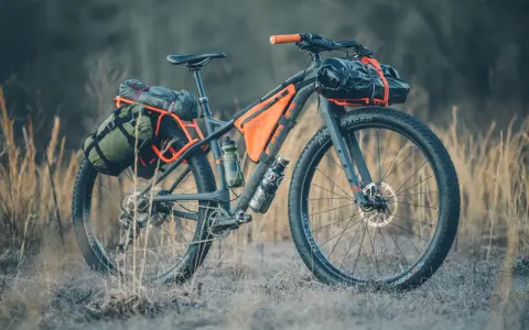 A fully loaded bike camping setup with panniers, frame bags, and handlebar roll, ready for an adventure.