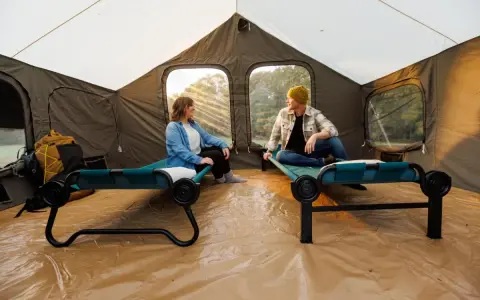 Two people relax on cots inside a large tent, showcasing smart tent camping hacks for comfort and organization.