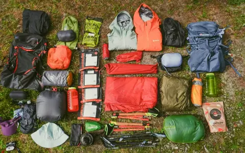 A comprehensive fastpacking gear list, including backpacks, sleeping bags, tents, jackets, food, and trekking poles, laid out on grass.