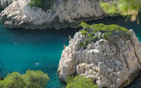 Adventurous swimmers enjoy the turquoise waters of the calanques of Cassis, with some daring to cliff jump from rocky outcrops.
