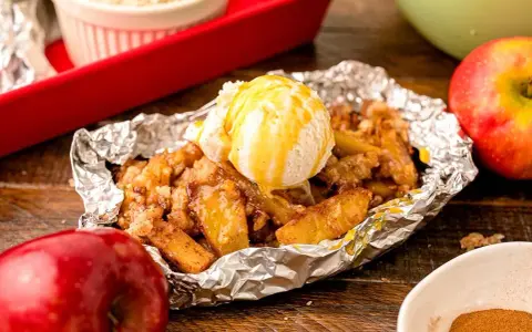 Warm campfire apples, baked in foil, topped with a scoop of vanilla ice cream and drizzled with caramel.