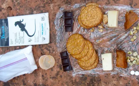 Backpacking lunch ideas no cooking: crackers, cheese, chocolate, dried peas, and jerky laid out on a map.