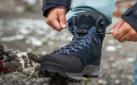 Hands tying laces on a new pair of Han Wag hiking boots, ready for breaking them in on the trail.