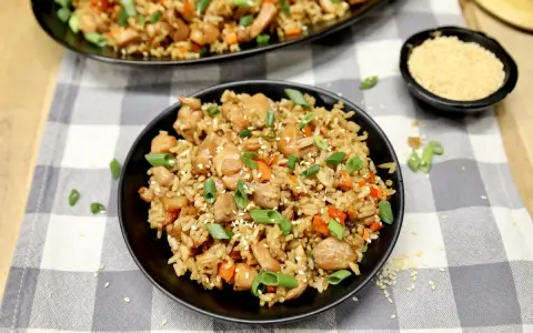 Chicken fried rice, a delicious dish perfect for learning how to cook rice on a Blackstone. Garnished with green onions and sesame seeds.
