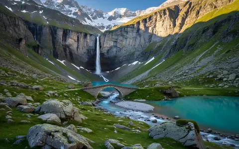 A breathtaking view of a waterfall cascading into a turquoise lake, with a stone bridge crossing a stream. This scene evokes the feeling of hiking in the Pyrenees, France, surrounded by majestic mountains and lush green slopes.