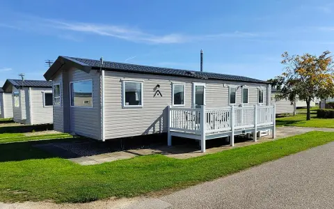 A row of modern mobile homes, perfect for a **location vacances mobil home**, sit under a clear blue sky.