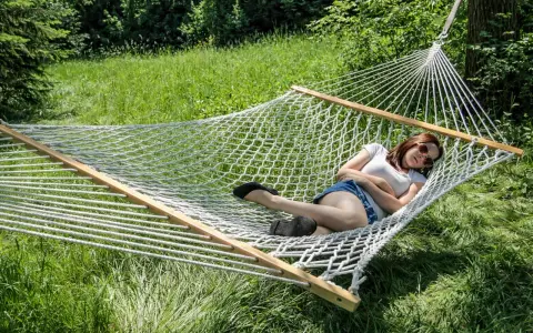A woman relaxes in a spacious double hammock, enjoying a sunny day outdoors.